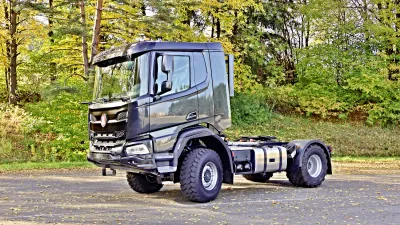 Tmavý nákladní vůz Tatra Phoenix u stromů